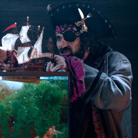 Um pirata brinca com um navio de brinquedo em um aquário
