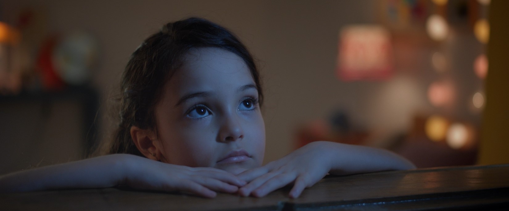 Uma menina apoiada em uma janela olha para o céu