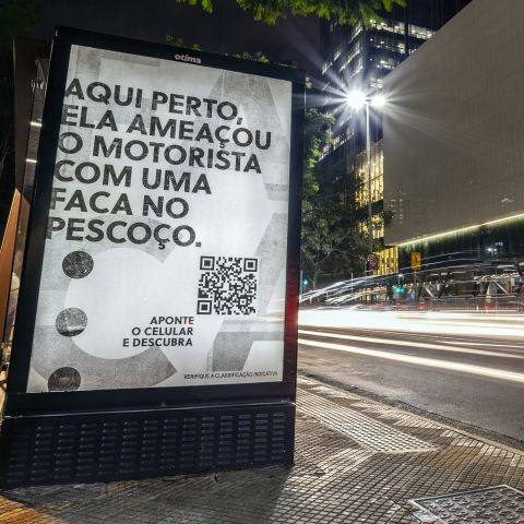Em um ponto de ônibus em São Paulo, um mobiliário urbano para a segunda temporada da série "Garota da Moto". Na peça publicitária há o texto: aqui perto, ela ameçou o motorista com uma faca no pescoço. Aponte o celular e descubra. Há um QR Code abaixo do texto