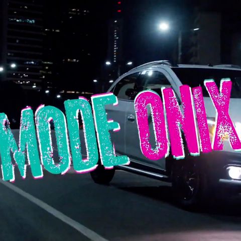 À noite, o Chevrolet Onix percorre uma rua. Há o logo Lollapalooza e o texto: Mode Onix