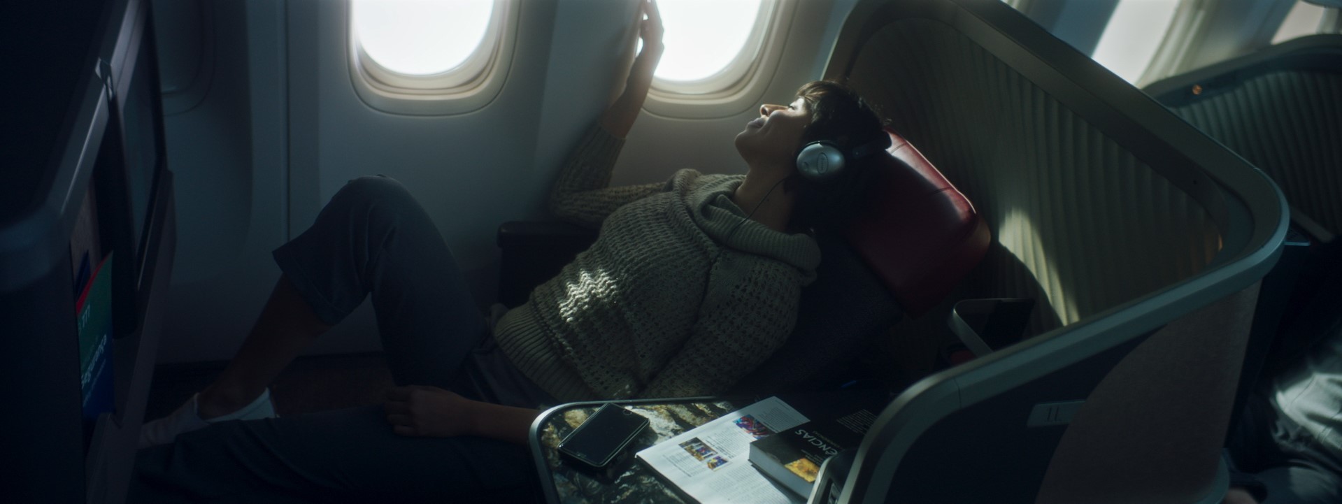 Mulher usando fone de ouvido sentada em cadeira de avião durante um voo.