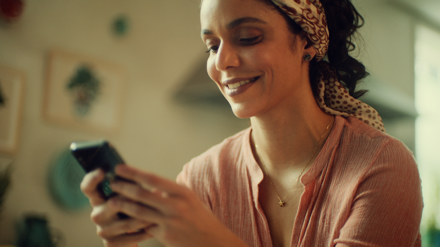 Foto de uma mulher com leve sorriso enquanto usa o celular